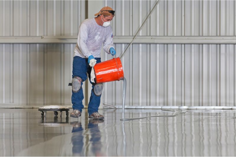 Epoxy resin being poured and spread across a garage floor
